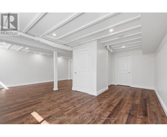 A room with wooden flooring and white walls, with a door and a window.