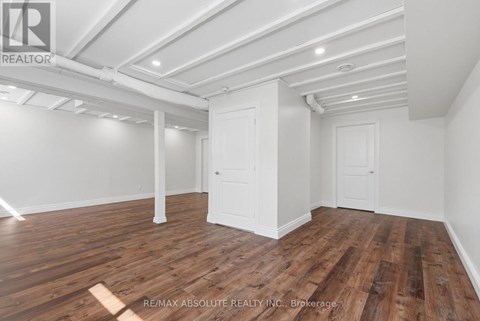 A room with wooden flooring and white walls, with a door and a window.