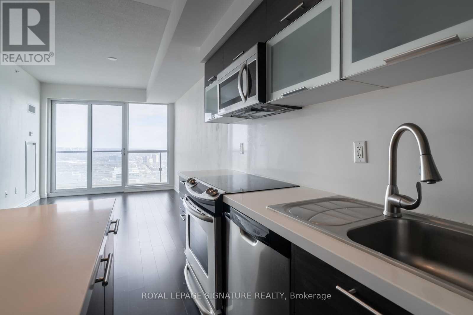 A modern kitchen with stainless steel appliances and a large window.