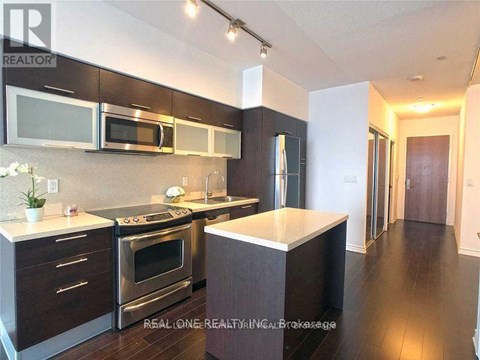 A modern kitchen with dark wood cabinets and stainless steel appliances.