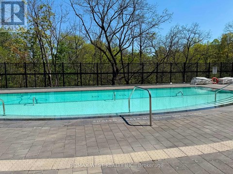 A pool surrounded by a black fence with trees in the background.