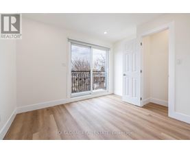 A room with a white door and a window with a view of a fence and trees.