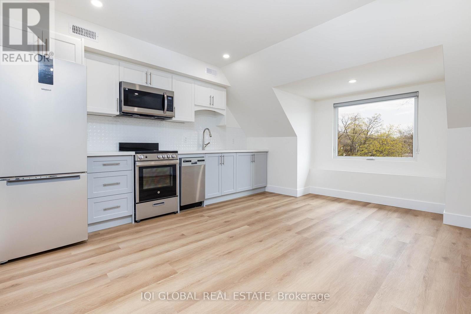 A modern kitchen with white appliances and wooden flooring.