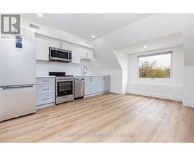 A modern kitchen with white appliances and wooden flooring.