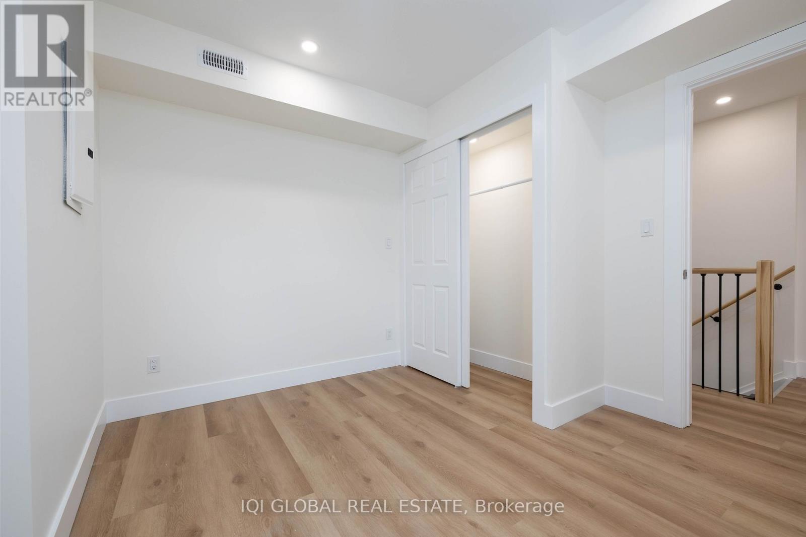 A spacious room with wooden flooring and white walls.