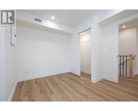 A spacious room with wooden flooring and white walls.