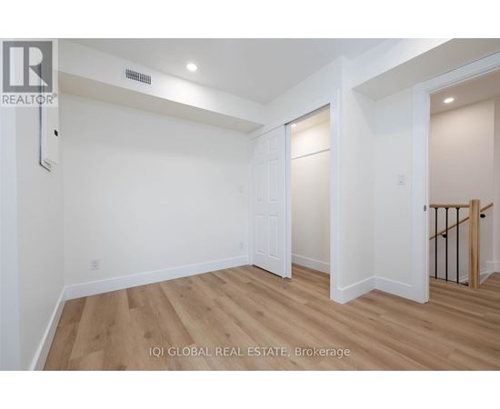 A spacious room with wooden flooring and white walls.