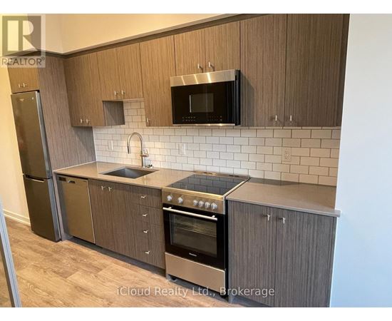 A kitchen with wooden cabinets and a stainless steel refrigerator.
