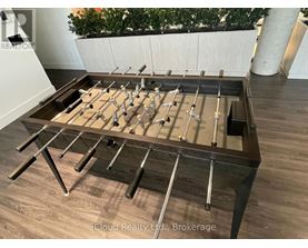 A pool table with a brown felt cloth and metal legs.