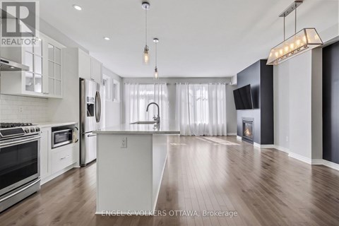 A modern kitchen with stainless steel appliances and a wooden floor.