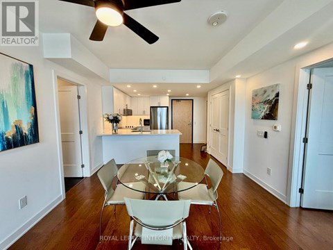 A spacious living room with a large beige sofa and a dining area in the background.