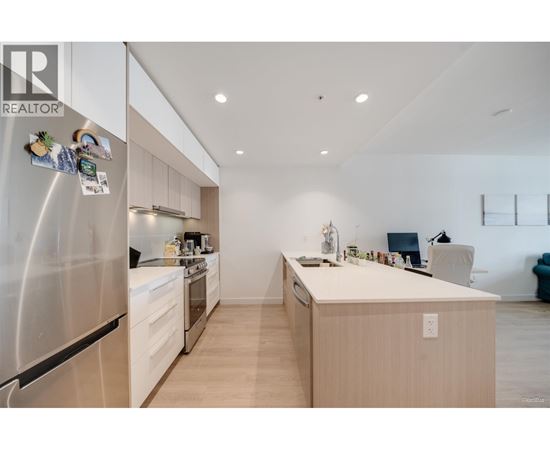 A modern kitchen with a stainless steel refrigerator and wooden cabinets.
