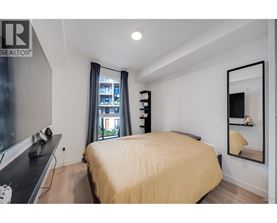 A bedroom with a bed, a desk, and a window with a view of a building outside.