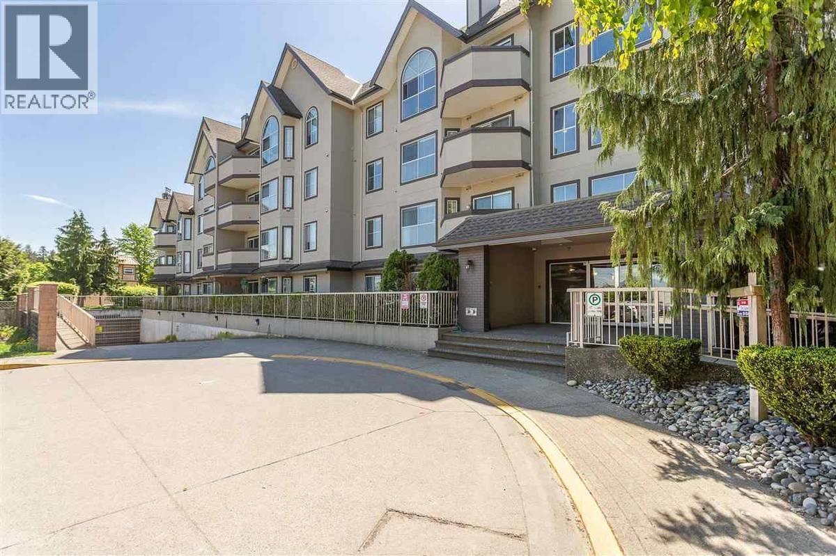 A large apartment complex with a parking lot in front.