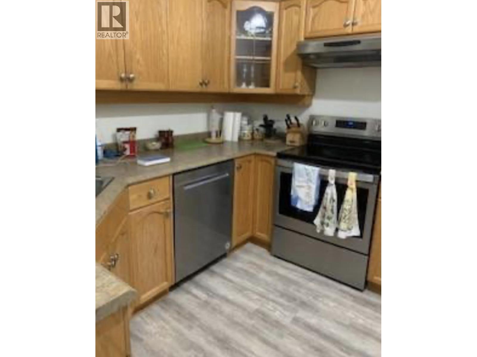 A kitchen with wooden cabinets and a black dishwasher.
