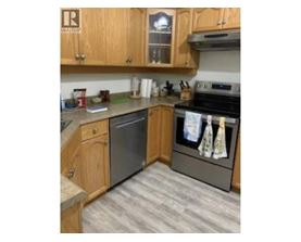 A kitchen with wooden cabinets and a black dishwasher.