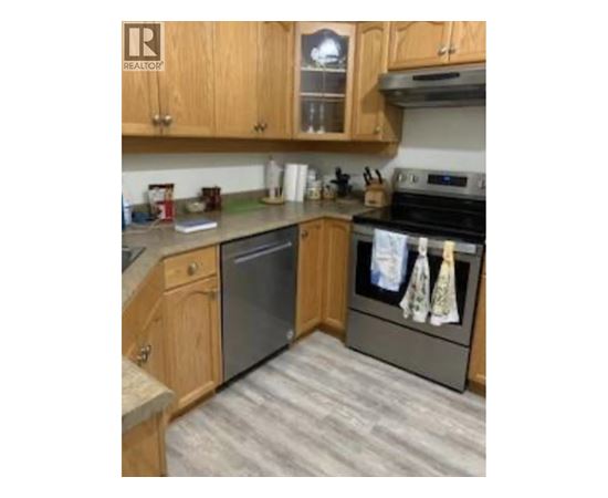 A kitchen with wooden cabinets and a black dishwasher.