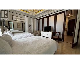 A bedroom with a large bed and a chandelier.