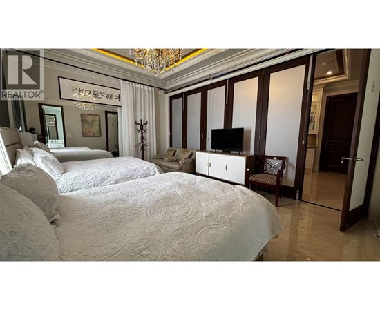 A bedroom with a large bed and a chandelier.