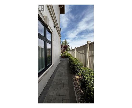 A long, narrow walkway with a metal fence on one side and a building with a glass window on the other.