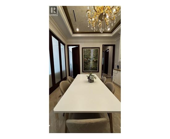 A dining room with a white table and chairs.