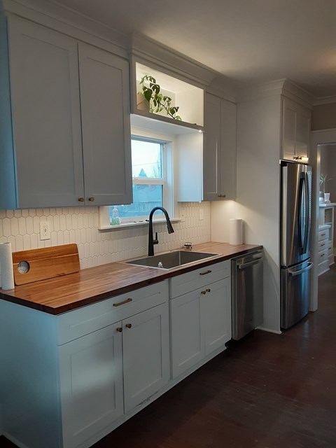 A kitchen with white cabinets and a wooden countertop.