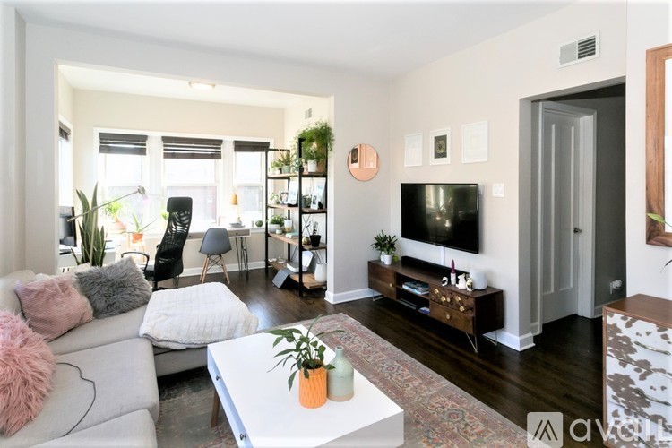 A living room with a white couch, a coffee table, and a television.
