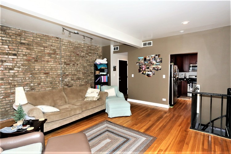 A living room with a couch, chair, and a brick wall.