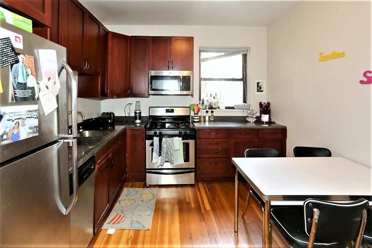 A kitchen with wooden cabinets and a stainless steel refrigerator.