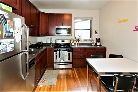 A kitchen with wooden cabinets and a stainless steel refrigerator.