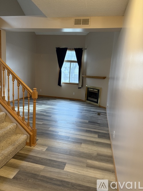 A room with wooden stairs and a window with a black curtain.