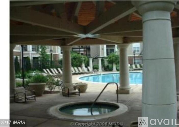 A pool area with a hot tub and lounge chairs.