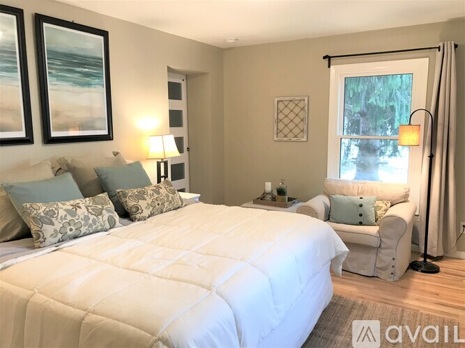A bedroom with a large bed and a window with a view of trees.
