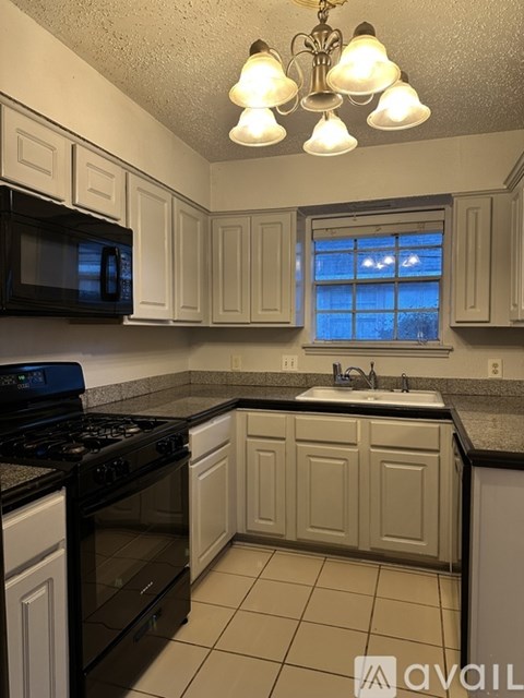 A kitchen with black appliances and white cabinets.