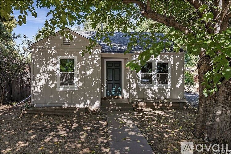 A small, old house with a tree in front.
