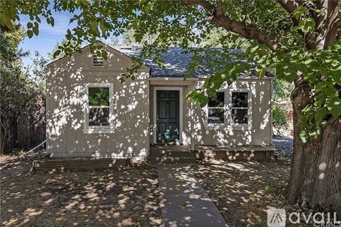 A small, old house with a tree in front.
