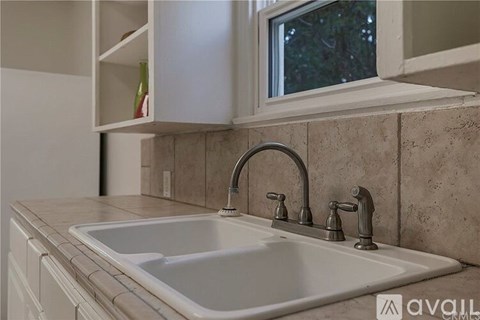 A kitchen sink with a chrome faucet and a window above it.