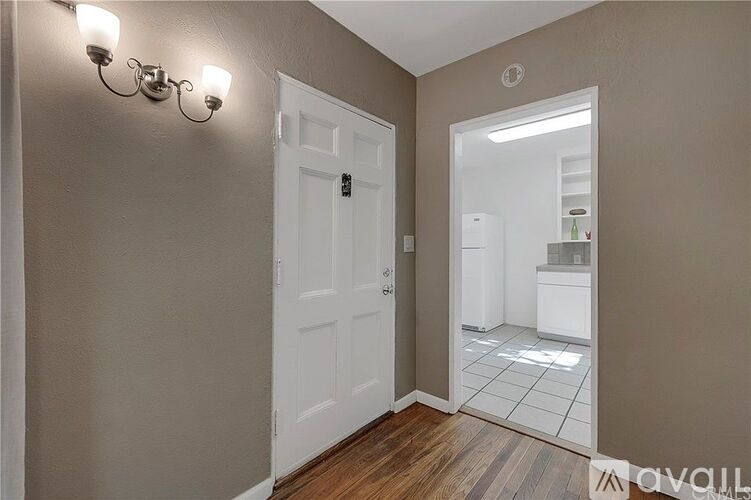 A white door is in a hallway with lights on the wall.