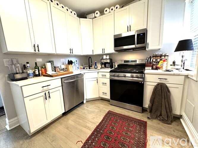 A kitchen with white cabinets and a red rug on the floor.