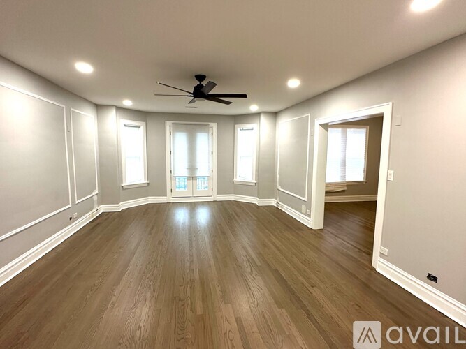A spacious room with wooden flooring and a ceiling fan.