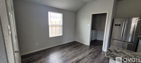 A kitchen with a refrigerator and a wooden floor.