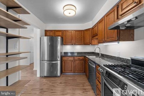 A kitchen with wooden cabinets and a stainless steel refrigerator.