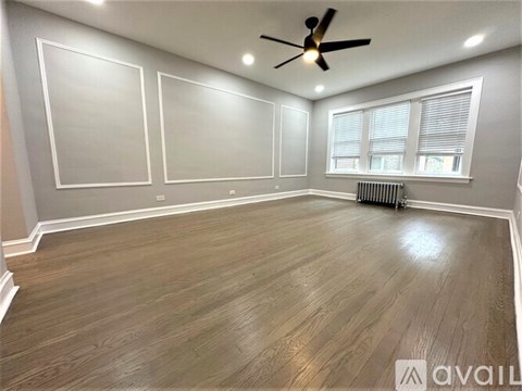 A spacious room with wood flooring and a ceiling fan.