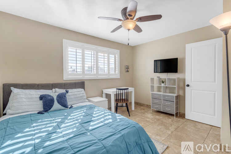A bedroom with a bed, a ceiling fan, and a television.