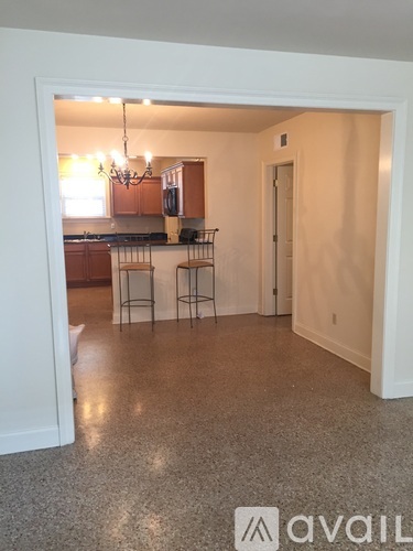A kitchen area with a bar stool and a chandelier.