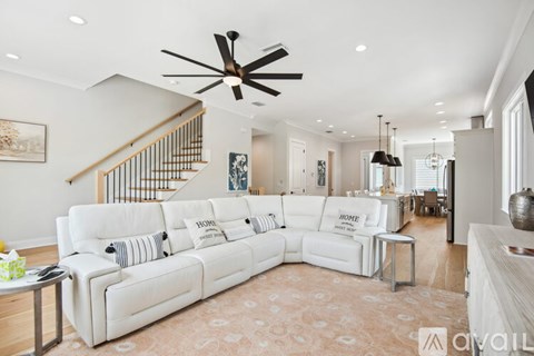 A living room with a white couch and a ceiling fan.