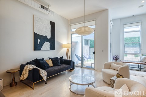A living room with a black couch and a large painting on the wall.