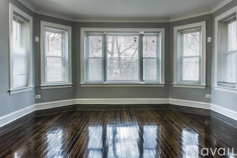 A room with wooden floors and three windows.