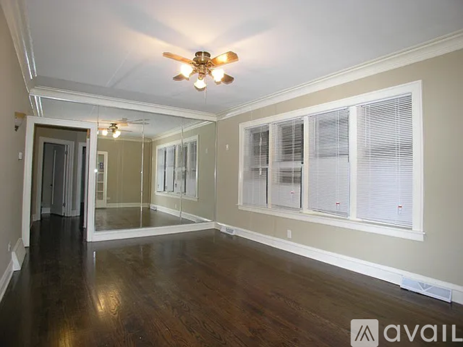 A spacious room with a ceiling fan and wooden flooring.