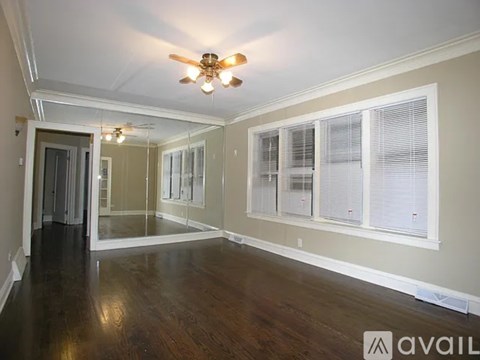 A spacious room with a ceiling fan and wooden flooring.